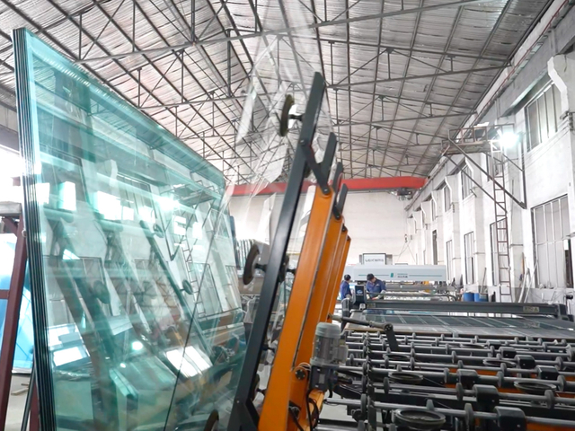 Glass handling machine lifting large glass panels in factory workshop